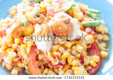 Closeup Corn salad and Salted egg in blue plate, Thai people call Som Tam Khow Phod Kai Khem.