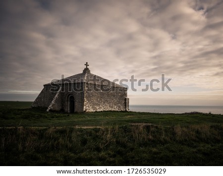 A wide angle shot of St Aldhelm's chapel in the UK under a clouded sky