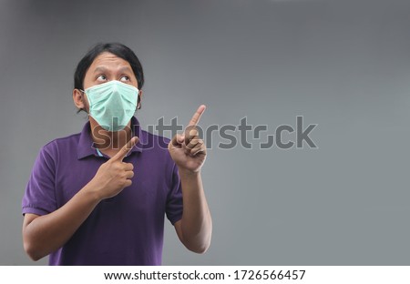 asian man with face mask or masker hand finger pointing space isolated on grey background Royalty-Free Stock Photo #1726566457