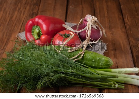 Fresh red tomatoes, bell pepper, cucumbers, onions and fresh herbs on a wooden background. Vegetarian food.
