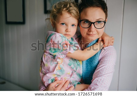 picture of lovely young caucasian female with pretty face, short dark hair, big eyes holds her child and rejoices