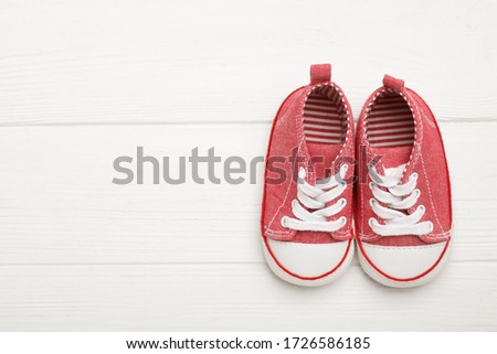 Top view of child's booties on white wooden background, space for text