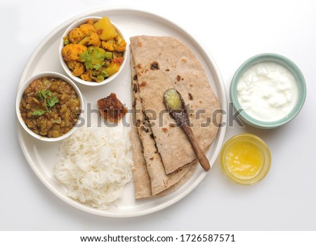 Veg Thali or Vegetarian Indian food plate with roti or flat bread, ghee butter, rice, curd, cauliflower curry and daal or lentil Royalty-Free Stock Photo #1726587571