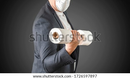 A man in medical mask is panic buying tissue toilet paper during Coronavirus outbreak or Covid-19, Concept of Covid-19 quarantine and panic buying and storing toilet tissue in Europe.
