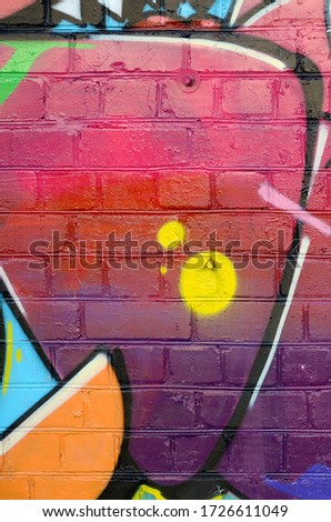 Abstract colorful fragment of graffiti paintings on old brick wall. Street art composition with parts of unwritten letters and multicolored stains. Subcultural background texture