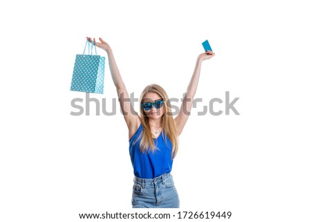 A girl in a bright blue jeans and blouse with blue bags in her hand and a credit card after shopping. A happy young lady returns with shopping from the Mall. Isolated on a white background