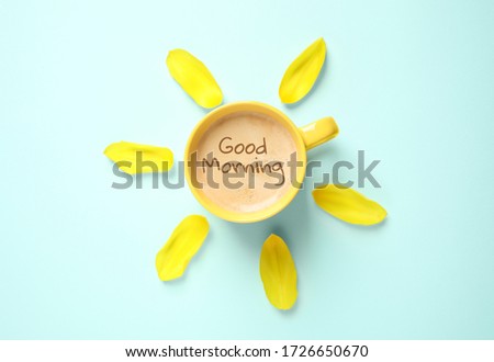 Cup of aromatic coffee and flower petals on light blue background, flat lay. Good morning