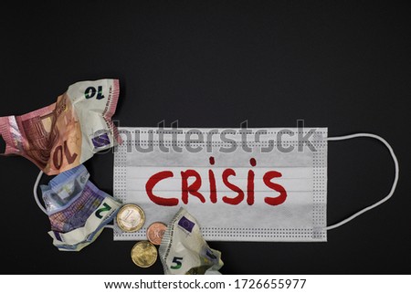 Top view of surgical mask with crisis written on red and crumpled euro banknotes representing the financial crisis