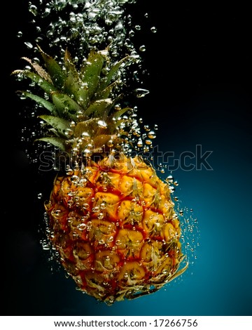 Fresh pineapple in water on a black/blue background with air bubbles