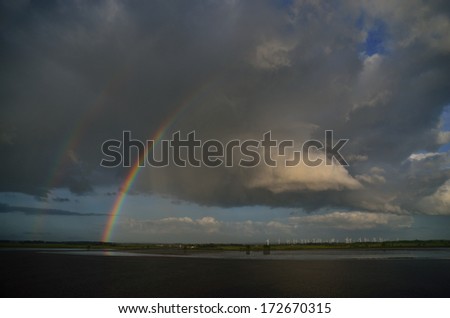 beautiful double rainbow with many windmills at sea