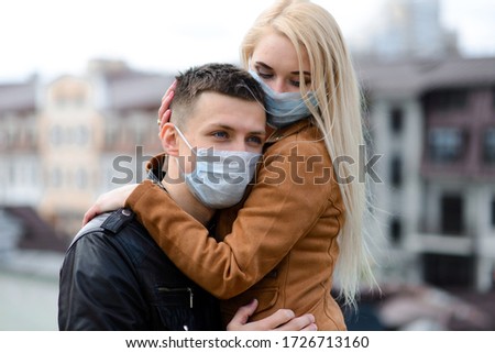 Couple wears a medical mask walking on the street of the city during the spread of news about the epidemic of coronavirus. Love story.