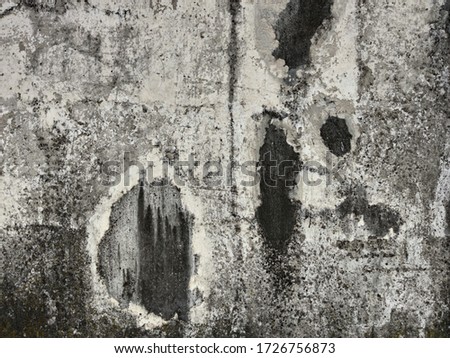 Old white wall of a building with gray and black spots.
