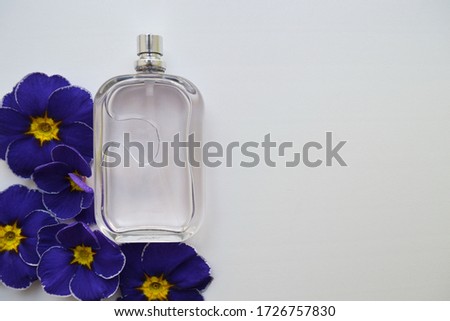 Perfume bottles and flowers on white background, top view. Flat lay arrangement with space for text. Mockup branding cosmetics.