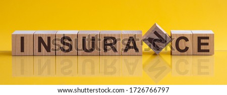 INSURANCE message word on a wooden desk on cube blocks with a green nature background
