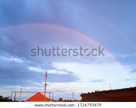 Rainbow over the village. Rainbow after rain.