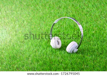 White headphones on the green artificial grass 