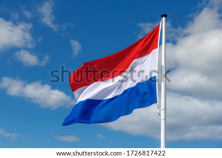 National flag of the Netherlands with horizontal tricolour of red, white and blue, Dutch flag waving on the air in a sunny day and blue sky background.