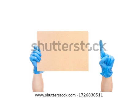 protest symbol empty cardboard paper poster hold hands in blue medical glove and pointing index finger up, concept mockup strike paramedics medical crisis isolated on white background with copy space.