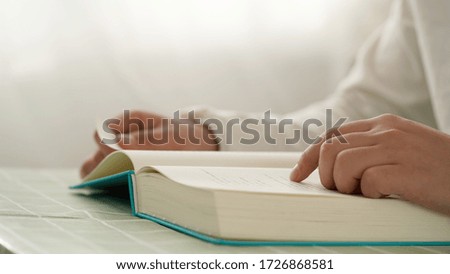 Closeup of woman sitting at desk and carefully reading with finger moving across the page