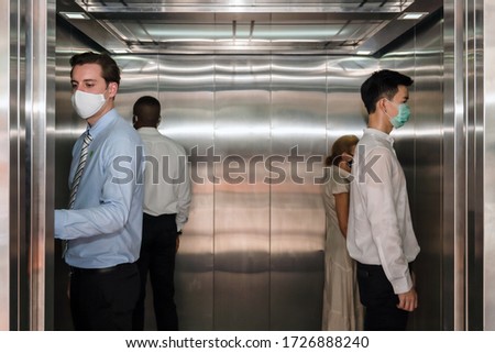caucasian business man and other people standing apart from each in corner of elevator for social distancing to avoid coronavirus covid-19 spreading, selective focus