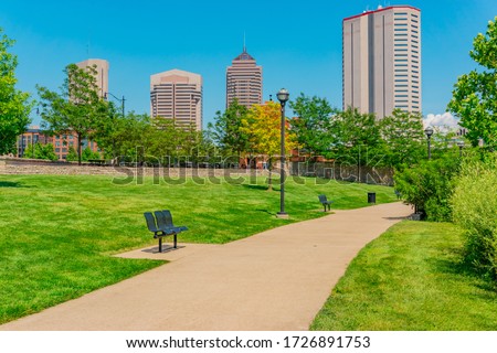 Spring day at Columbus, Ohio in the park next to the downtown district.  A grass lined path leads through the park and benches are there for relaxing.