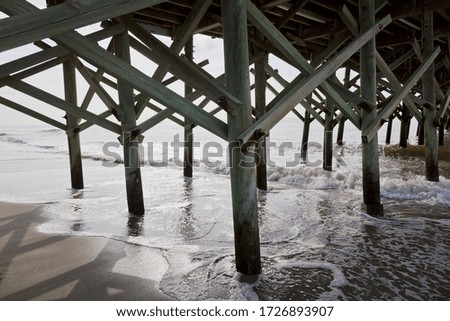 The underneath part of a pier with foamed ocean water