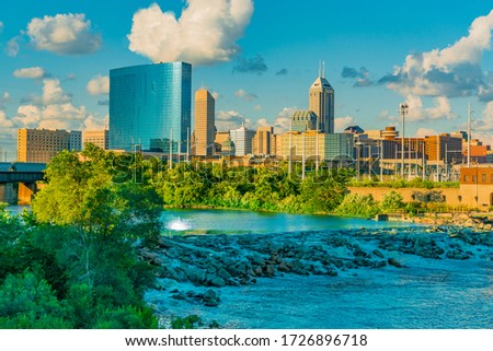 The cascading White River and the skyline of Indianapolis, Indiana both glow in the last light of the day.