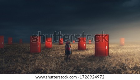 Traveler with a backpack on field with multiple doors . Hard choices concept . Difficult decision and ways to unknown future. Royalty-Free Stock Photo #1726924972