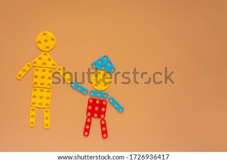Male and child figures made of build and design mosaic puzzles on beige background with copy space.