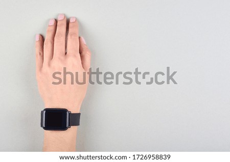 Hand with black smart watches on grey background. Flat lay, overhead view image. Copy space, template.