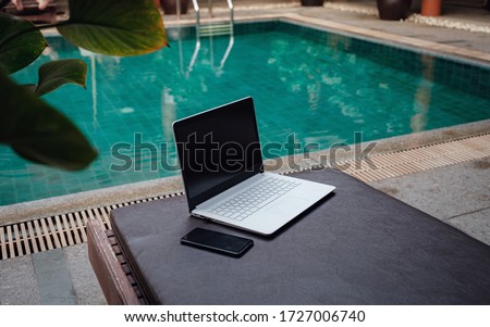 Laptop at the swimming pool and smartphone