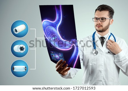 Doctor against the background of a hologram of the stomach, A camera the size of a capsule in the stomach, an endoscopy procedure. Digestive tract disease concept. Mixed medium, copy space Royalty-Free Stock Photo #1727012593