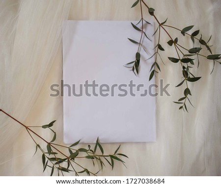 Green leaves on a blank white sheet for text. With a white tulle fabric background and copy space.