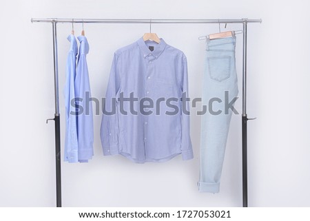 Three blue long sleeved shirts with blue jeans on hanger