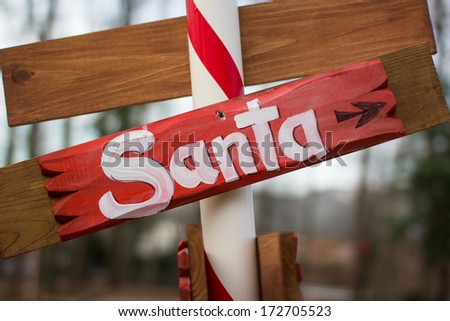 Handmade wooden Santa sign, mounted on candy striped pole.