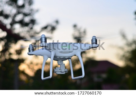 beautiful white drone flying at sunset front of blurred trees for take aerial photo landscape by gimbal camera.