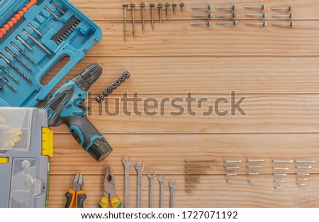 
Hand tools, drills, and screws made from steel, each type of screw nut On a wooden background table (top view) with free space.
