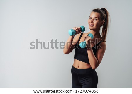 Girl Holding Dumbbells like a Boxer Standing Front To Camera Over Gray Background