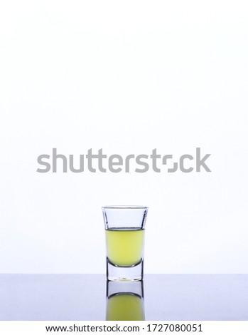 Yellow water in little glass isolated white background