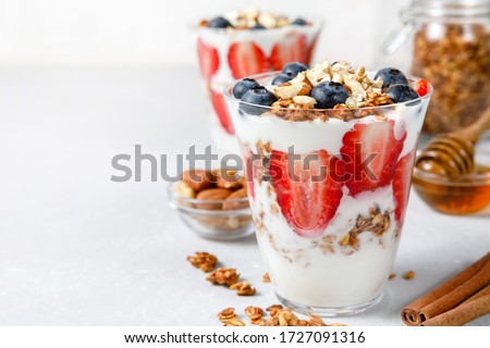 Granola Parfait with greek yogurt, oat granola, fresh berries, honey and mint leaves in tall glass jar. Healthy breakfast concept. Organic oat, almond and sunflower seeds. Royalty-Free Stock Photo #1727091316