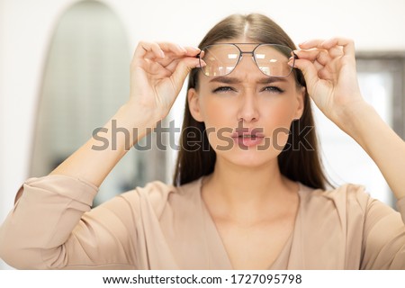 Poor Eyesight Concept. Portrait of beautiful young woman with spectacles squinting, trying to look closer, copy space Royalty-Free Stock Photo #1727095798