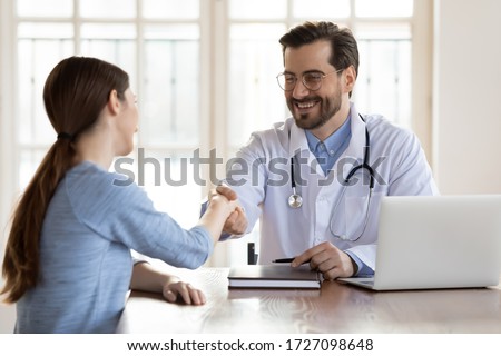 Smiling young Caucasian male doctor shake hand greeting get acquainted with female patient in hospital, happy man physician handshake woman client make agreement sign health insurance in clinic Royalty-Free Stock Photo #1727098648