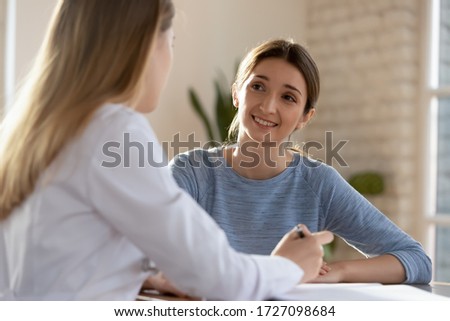 Smiling millennial woman visit female doctor consulting about health complains, happy satisfied young client talk discuss treatment prescription with GP or physician at appointment in hospital Royalty-Free Stock Photo #1727098684