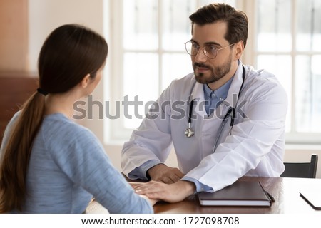 Young Caucasian male GP hold female patient hands show support and understanding at consultation, supportive man doctor comfort millennial woman client, help deal with bad results or miscarriage Royalty-Free Stock Photo #1727098708