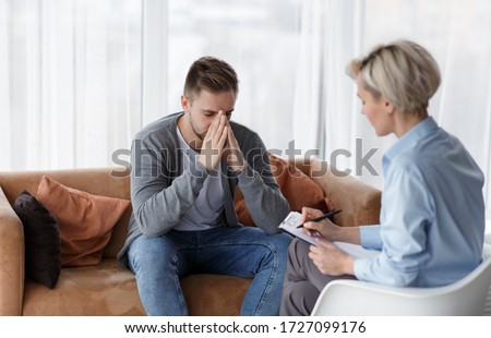 Depression Counseling. Desperate Man Telling About Unhappy Life While Professional Psychologist Taking Notes During Appointment In Office. Selective Focus Royalty-Free Stock Photo #1727099176