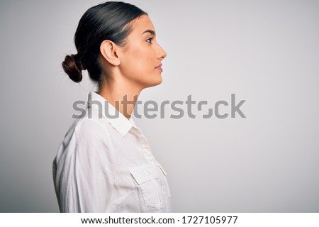 Young beautiful brunette woman wearing casual shirt over isolated white background looking to side, relax profile pose with natural face with confident smile. Royalty-Free Stock Photo #1727105977