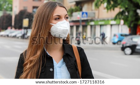 COVID-19 Pandemic Coronavirus Woman in city street wearing KN95 FFP2 mask protective for spreading of disease virus SARS-CoV-2. Girl with protective mask on face against Coronavirus Disease 2019. Royalty-Free Stock Photo #1727118316