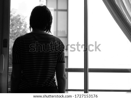 Silhouette of a woman trapped at home with violent man during the great lock down. Sign of domestic violence Royalty-Free Stock Photo #1727153176