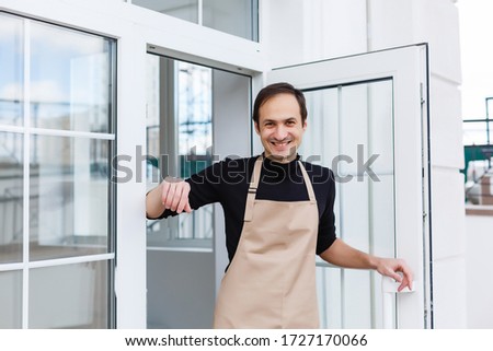 Portrait of a waiter showing open sign at the coffee shop