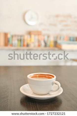 White coffee mug on wooden table, background, bookshelf.